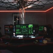 Team of hackers with Guy Fawkes masks coding in a dark room with computers.